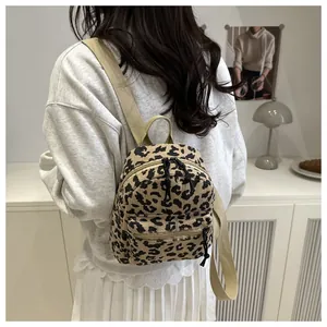 Makroaufnahme der Leoparden-Cord-Textur und des beigen Segeltuchgurts am Mini-Rucksack