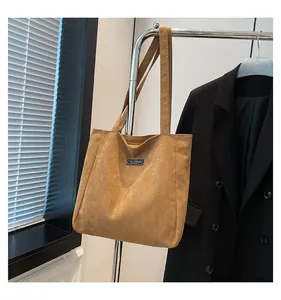 Détail du cabas en daim marron avec étiquette en tissu Fashion Instinct et de longues anses
