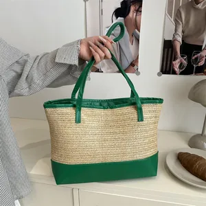 Large straw tote bag with green contrast trim and handles shown in a lifestyle setting