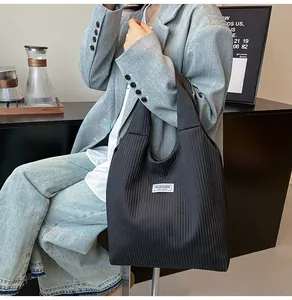 Detail of black pleated corduroy tote bag with Fashion Instinct label on wide strap