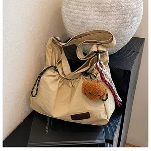 Détail du sac bandoulière en nylon kaki avec pendentif chien et écusson de mode
