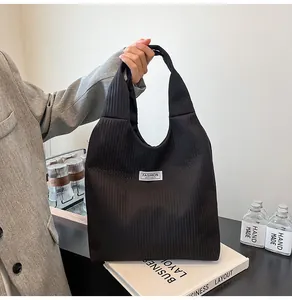 Detail of black corduroy tote bag showing the vertical texture and fashion patch label