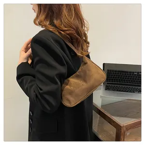 Detail van een donkerbruine suède schoudertas met een minimalistische retro-esthetiek