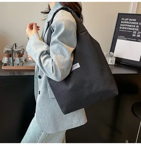 Detail of black corduroy tote bag featuring vertical texture and wide shoulder strap