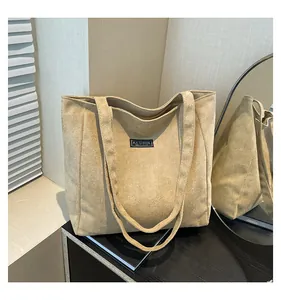 Détail du sac cabas en daim beige avec écusson de mode et bandoulière longue pour femmes