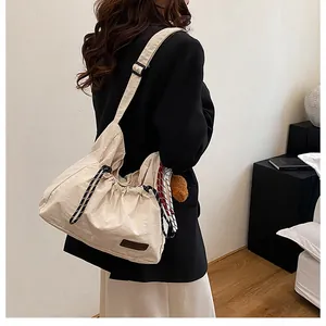 Détail du sac bandoulière en nylon crème avec cordon de serrage et cordon tissé