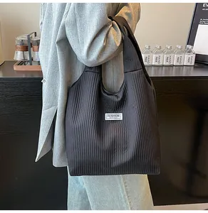Close-up of black corduroy tote bag with Fashion Instinct label worn by a model