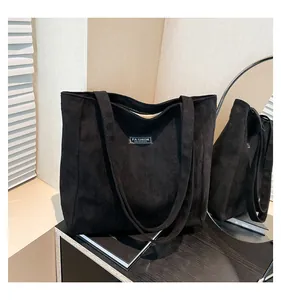 Détail d'un sac cabas noir en daim avec étiquette Fashion Instinct et texture douce