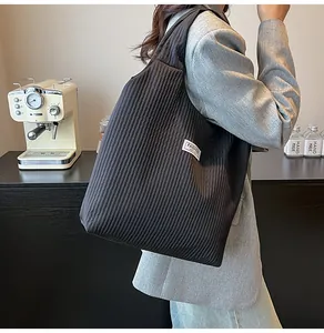 Detail of black quilted corduroy tote bag featuring white Fashion Instinct woven label