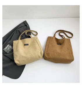 Détail de cabas en daim beige et marron café avec étiquette Fashion et longues anses