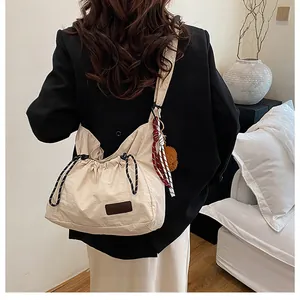 Détail du sac à bandoulière beige à cordon avec charm ours en peluche et foulard en soie