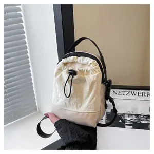 Close-up of off-white nylon drawstring crossbody bag with leather trim and black straps