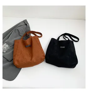 Vue à plat de sacs fourre-tout minimalistes en daim marron et noir avec étiquette tissée
