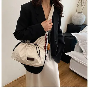 Détail du sac à cordon en nylon crème montrant la bandoulière en corde et le tissu texturé