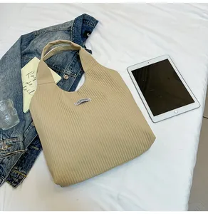 Detailed texture of beige corduroy tote bag showing vertical ribs and fashion label