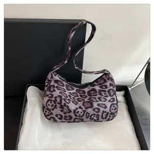 Detailopname van mini paarse hobo tas met luipaardprint op witte satijnen stof