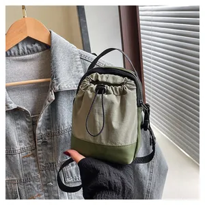 Close-up of green nylon drawstring crossbody bag styled on a denim jacket background