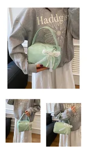 Detail of mint green handbag featuring decorative pearl lace bow and smooth texture