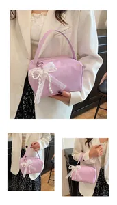 Detail of light purple handbag featuring a white lace bow charm and pearl accents