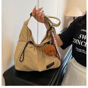 Détail du sac bandoulière en nylon kaki avec charme ours en peluche et cordon tressé