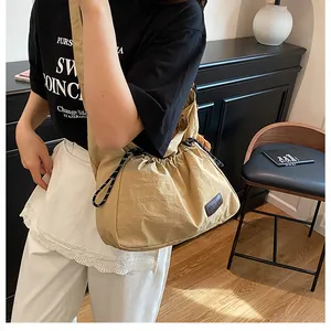 Détail du sac bandoulière en nylon kaki avec cordon de serrage et écusson de mode devant