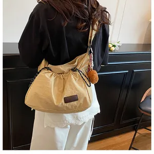 Détail du sac bandoulière en nylon kaki avec pompon marron et étiquette FASHION brodée