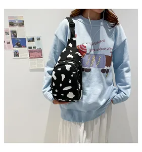 Canvas chest bag with black and white cow print and adjustable strap shown on model