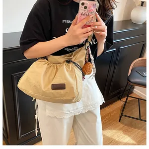 Détail du sac à bandoulière en nylon kaki avec cordon de serrage et breloque petit ours