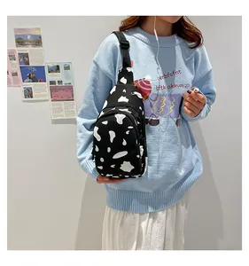 Detail shot of a canvas cow print chest bag with adjustable strap on a female model