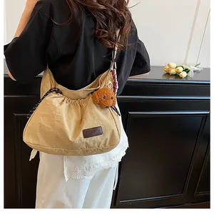 Détail du sac bandoulière kaki avec cordon de serrage, charme ours et écusson fashion