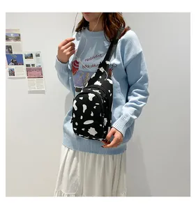 Detail of cow print canvas chest bag worn by model over a blue sweater
