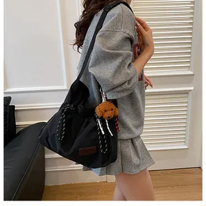 Détail du grand sac bandoulière en nylon avec fermeture à cordon et étiquette mode