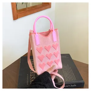 Detailed knit texture of pink heart handbag with soft shoulder strap and curved handle