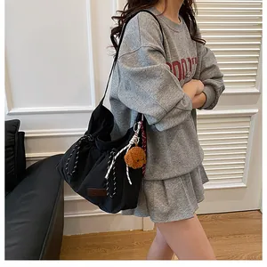 Détail du sac bandoulière en nylon noir avec cordon et charm ours en peluche doux