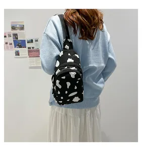 Close-up of cow print canvas chest bag with dual zippers and adjustable black nylon strap