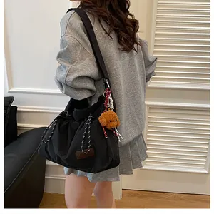 Détail du sac à bandoulière en nylon noir avec cordon de serrage et charmant ours en peluche