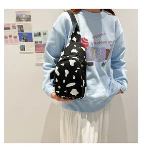 Detail of cow print canvas chest bag featuring dual zipper pockets and adjustable strap