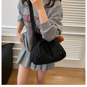 Détail du sac bandoulière en nylon noir avec cordon de serrage et breloque ours en peluche