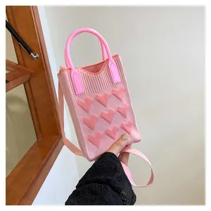 Detailed close-up of pink knitted mini bag texture with embossed heart and round handle