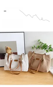Detail of corduroy tote bags in white and khaki with leather handles on a wooden table