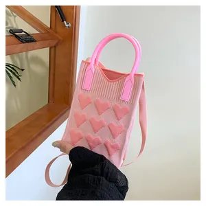 Detail of pink knitted crossbody bag with 3D heart patterns and bright pink handle