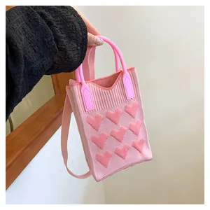 Detailed knit texture of pink heart-patterned mini tote bag with crossbody strap