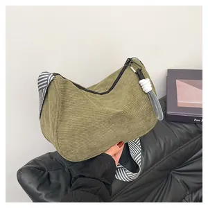 Detail der grünen Cord-Hobo-Tasche mit gestreiftem Gurt und Reißverschluss