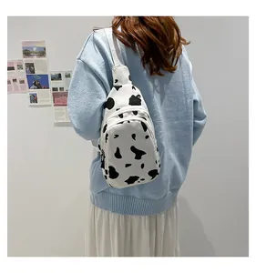 Close-up of canvas chest bag with cow pattern print, double zippers and adjustable strap
