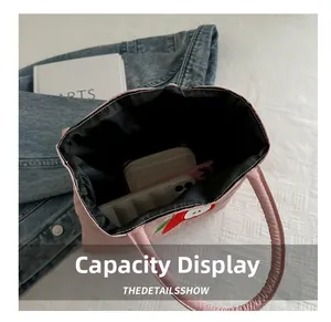Detail view of pink canvas tote interior with red apple embroidery and storage capacity