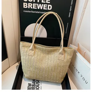 Dettaglio ravvicinato della trama a spina di pesce e manico in pelle beige della borsa