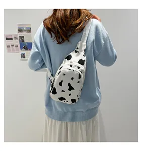 Close-up of cow print canvas chest bag with adjustable strap worn by a model