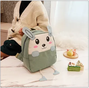 Détail d'un sac à dos lapin vert avec oreilles 3D posé sur une table en marbre blanc