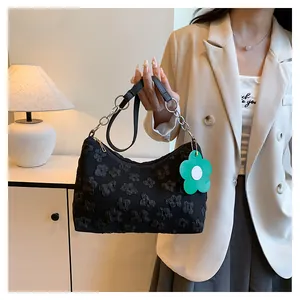 Detail of floral lace texture on black tote bag with green flower charm and chain strap
