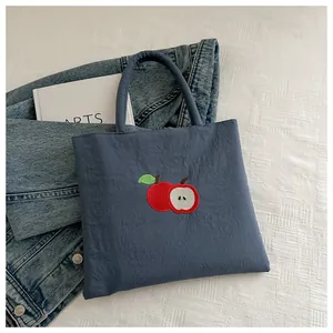 Detail of navy blue tote bag featuring premium apple embroidery on high-density canvas